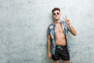 Fototapeta na wymiar Young caucasian man wearing a swimsuit showing number two with fingers.