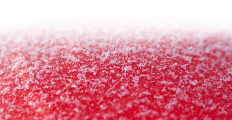 Real snow flakes on a red surface. Festive Christmas backdrop with snow closeup. White background, shallow depth of field