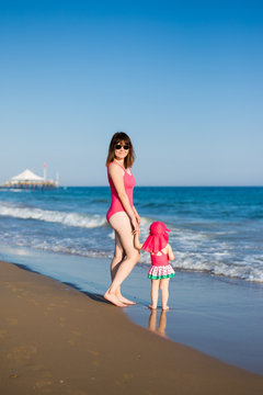 vacation and travel concept - portrait of happy mother walking with little daughter at the beach