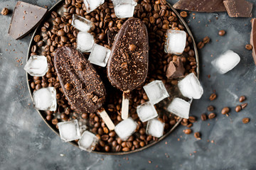 Chocolate ice cream on a stick on a gray background. Chocolate dessert. Ice. Coffee beans and chocolate.