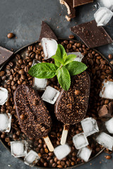 Chocolate ice cream on a stick on a gray background. Chocolate dessert. Ice. Coffee beans and chocolate. Fresh mint