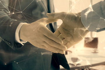 Multi exposure of tech theme hologram on office background with two men handshake. Concept of technology