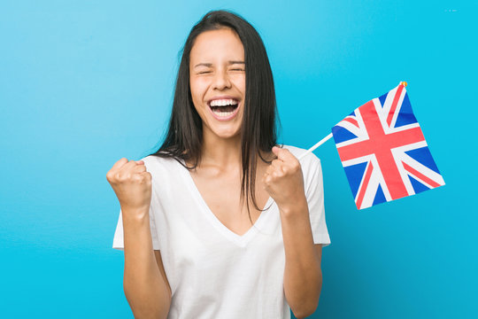 Young hispanic woman holding a united kingdom flag cheering carefree and excited. Victory concept.