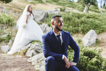 Beautiful wedding photo on mountain lake. Happy Asian couple in love, bride in white dress and...