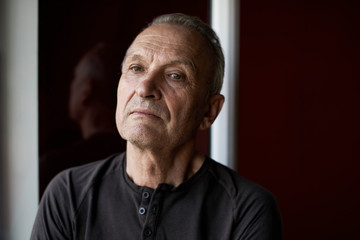 Fototapeta premium Portrait of serious handsome elderly man with gray hair, stylishly dressed , looking at camera against the background of window