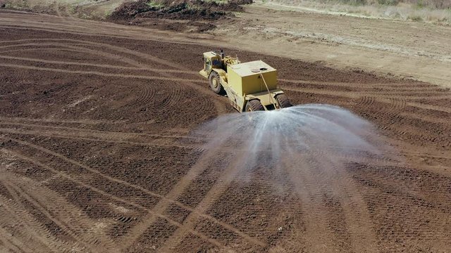 Articulated Water Truck spraying water on a large Excavation site  ground for Dust Suppression and Compaction