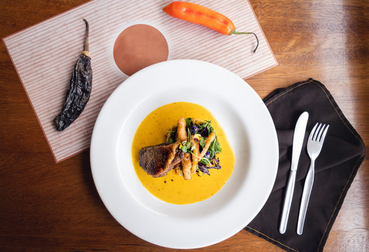 Grilled duck with rice in yellow pepper sauce, tempuras and a fresh green salad. Cutlery. Top view