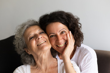 Cheerful senior mother and adult daughter posing at home. Happy elderly lady touching cheek of...