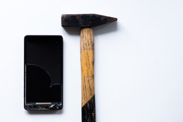 Broken touch mobile phone on white background and hammer