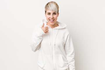 Young curvy woman wearing a white hoodie smiling and raising thumb up