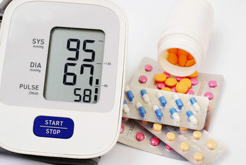 automatic blood pressure meter and pills on white background