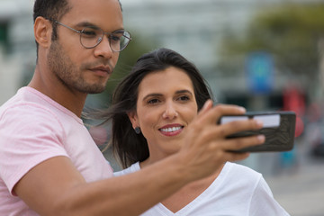 Happy multiracial couple taking self portrait with phone. handsome African American man holding smartphone in outstretched arm. Concept of self portrait