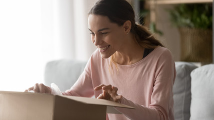 Happy satisfied young woman customer open parcel box at home