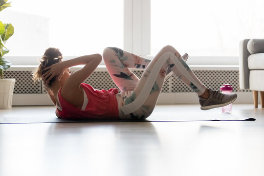 Young fit woman lying on mat doing bicycle crunch exercise