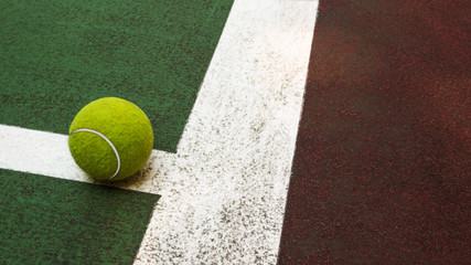 Yellow tennis ball hitting the sidelines on an green and orange artificial tennis court, sport...