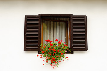 Wooden window with fresh red flower pots .