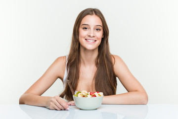 Young caucasian woman eating fruit bowl happy, smiling and cheerful.