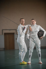 A portrait of two young women fencers looking at the camera