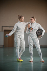 Two young women fencers looking to each other