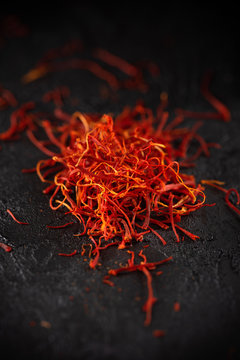 Saffron dry petals spices heap on dark slate stone table. Saffron flavor and coloring seasoning ingredient.