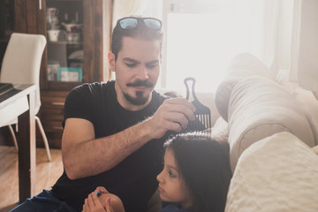 Father combing daughter at home