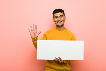 Young hispanic man holding a placard