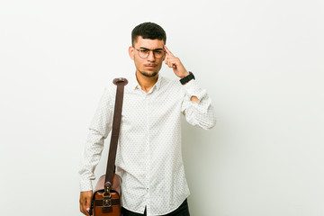 Young hispanic casual business man pointing temple with finger, thinking, focused on a task.