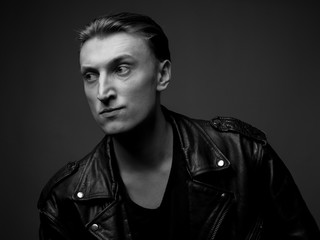Obraz premium Young man in a leather jacket. Studio portrait. Black and white