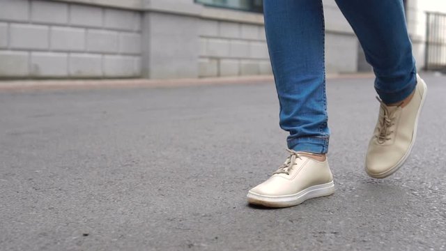 Shot of women feets in sneakers walking on tile road. Urban Environment.