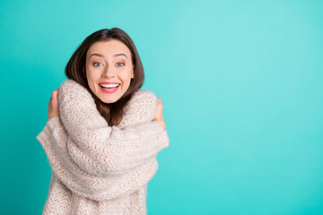 Portrait of crazy funky girl hug herself impressed by quality warm soft pullover scream wow omg isolated over teal turquoise color background