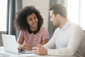 Multiracial company members sitting at desk talking and smiling