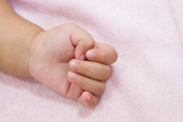 Right hand side of a baby on pink background. Newborn baby hand