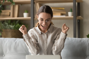 Overjoyed young woman express victory winning online bid on laptop