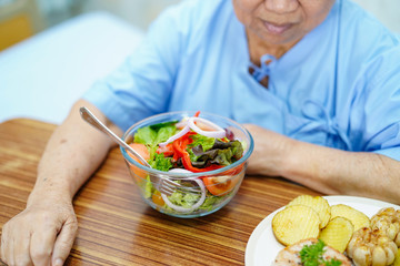 Asian senior or elderly old lady woman patient eating breakfast healthy food with hope and happy while sitting and hungry on bed in hospital..