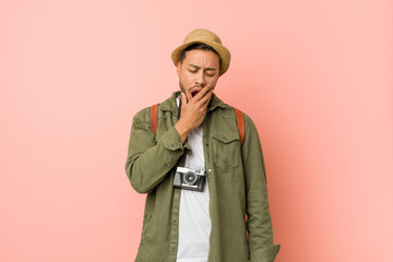 Young filipino traveler man yawning showing a tired gesture covering mouth with hand.