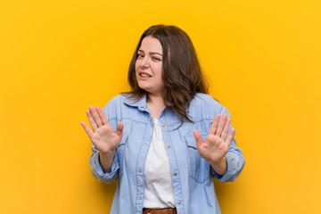 Young curvy plus size woman rejecting someone showing a gesture of disgust.
