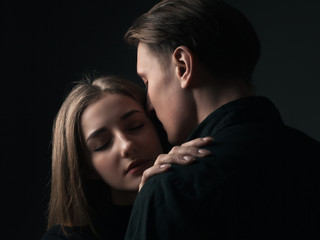 Young man and woman kissing in studio. Low key
