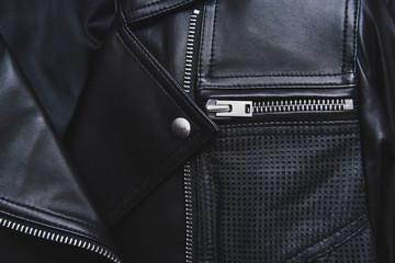 Black leather jacket with perforated elements. Metal zipper, clasp and button. Classic clothes for biker. Detailed closeup view. Beautiful background.