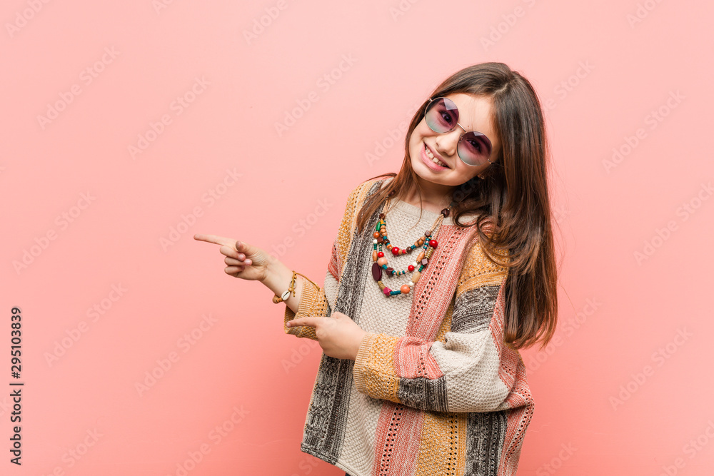 Wall mural Little hippie girl excited pointing with forefingers away.