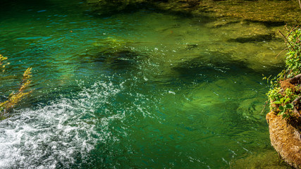 Green river surface with small waterfall
