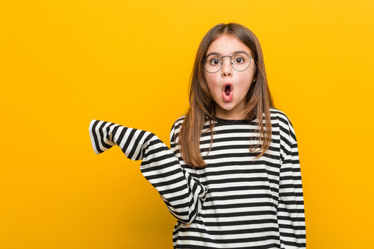 Little caucasian cute girl impressed holding copy space on palm.