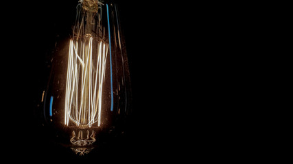 Lighting decor. Vintage hanging edison light bulb on a dark background. Old dusty light bulbs glowing in the dark. A lamp inside a decorative glass lamp. Light begins to appear and glow in the center.