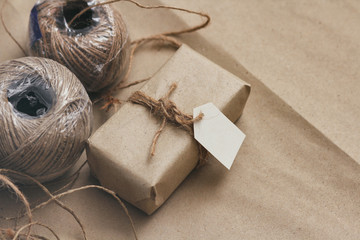 Parcel wrapping in brown craft paper and tie hemp string. Package with paper label. Delivery service. Online shopping. Your purchase. Gift box on a table. Hemp threads.	