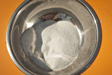 White paint in powder form. Texture of fine powder in a metal bowl. Paint for children's creativity.