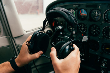 partial view of pilot in wristwatch holding headphones in plane