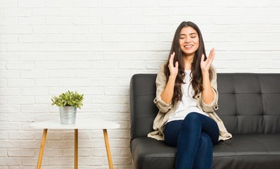 Young arab woman sitting on the sofa joyful laughing a lot. Happiness concept.