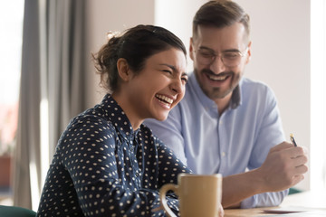 Happy young indian business woman laughing with male colleague in office