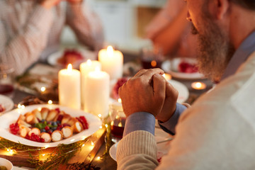 Close-up of senior man with beard sitting at the table and praying during Christmas dinner