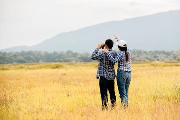 Asian couple  hiking in mountain  are exploring the forest using binoculars , Travel Teamwork explorer