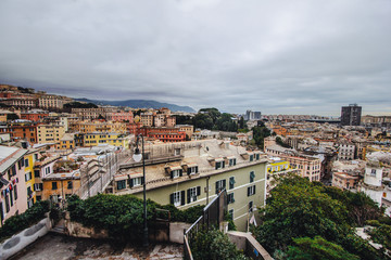 Fototapeta na wymiar Many beautiful old italian houses painted in bright colors with mountains on the background.An amazing cityscape of some public housing in Genova built in the 60s over hills of the city in cloudy day,